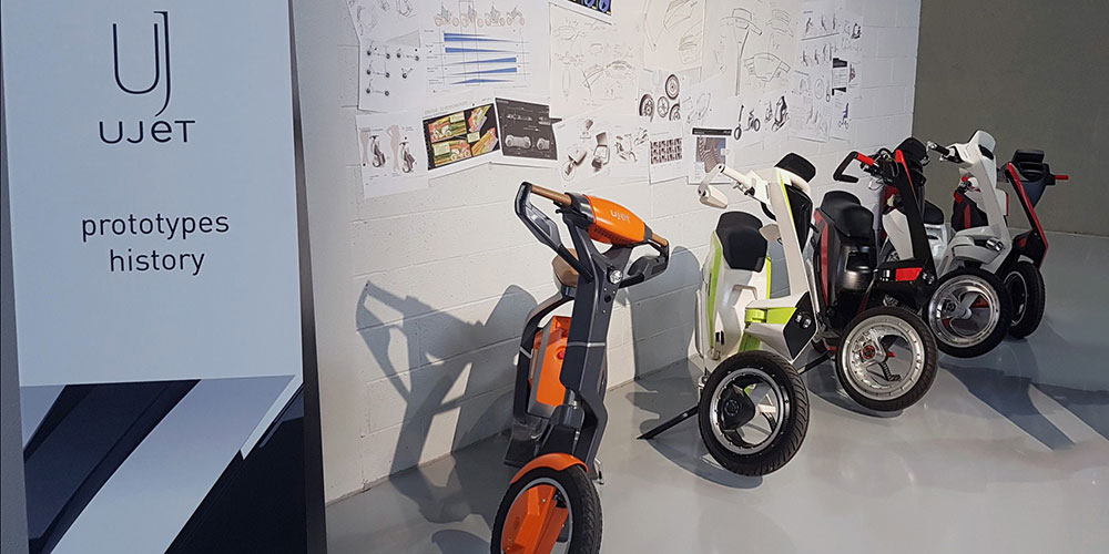 Exhibition detailing the history of UJET scooter prototypes, displayed alongside design sketches.